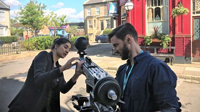 Two people setting up a special camera on the EastEnders set in Albert Square.