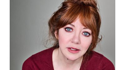 Diane Morgan in a v-neck dark red top looking at the camera.